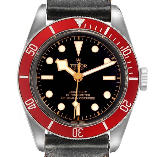 The image shows a frontal view of the Tudor Heritage Black Bay model 79230R, highlighting the black dial, red bezel, and black leather strap.